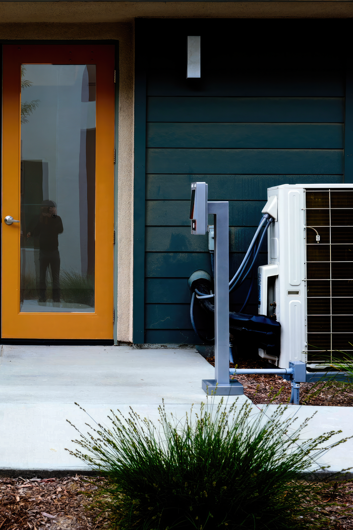 A modern house entrance featuring a yellow glass door and air conditioning unit outside.